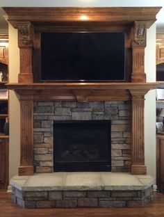 a fireplace with a flat screen tv mounted on it's mantle and some shelves