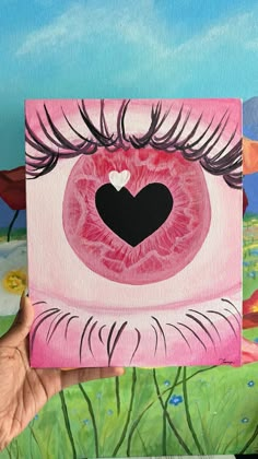 a person holding up a piece of art with a heart on it's eye