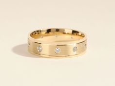 a yellow gold wedding ring with three diamonds on the inside and outside, sitting on a white surface