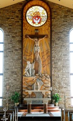 the interior of a church with stained glass windows and stone walls, including a crucifix