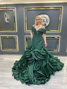 a woman in a green dress standing next to a wall with gold and silver decorations