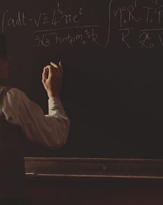 a man writing on a blackboard with chalk