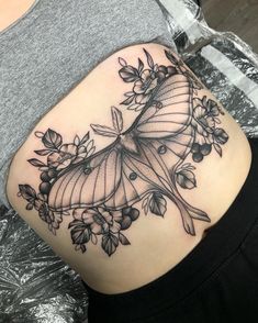 a black and white photo of a woman's thigh with a butterfly tattoo on it