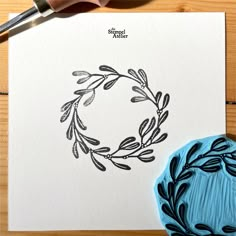 a paper with a wreath drawn on it next to a stamper and a rubber