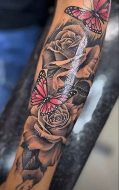 a woman's arm with roses and butterflies on it, in black and grey