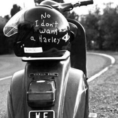 a green scooter parked on the side of a road with graffiti written on it