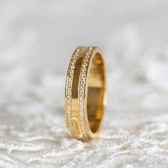 a close up of a wedding ring on a white surface with some diamonds in the middle