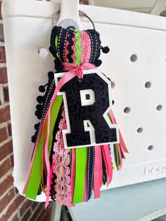 a key chain hanging from the side of a white door with pink, green and black ribbons