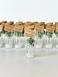 there are many small glass vases with flowers in them and labels on the bottles