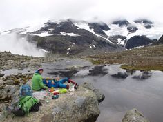 two people sitting on rocks in the mountains