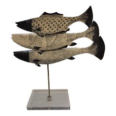 three wooden fish on a metal stand against a white background