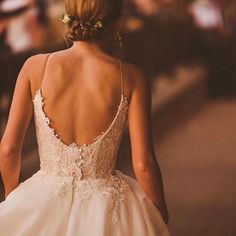 the back of a bride's wedding dress as she walks down the street with her hand in her pocket