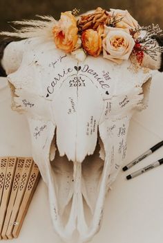 an animal's skull with flowers and writing on it