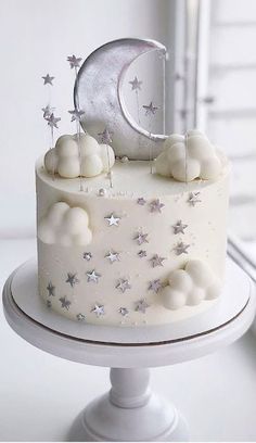 a white cake with silver stars and a crescent on top is sitting in front of a window