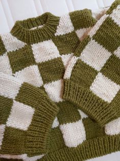 a green and white knitted blanket laying on top of a bed next to a pillow