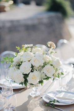 a long table is set with white flowers and silverware for an elegant wedding reception