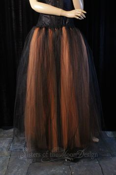 a mannequin wearing a black and brown tulle skirt on display in front of a black curtain