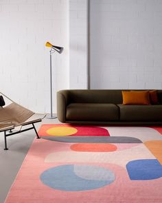 a living room with a couch, chair and rug on the floor in front of a white brick wall