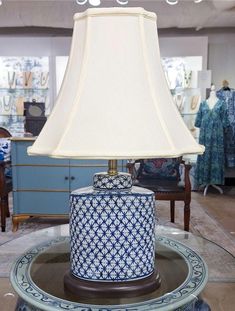 a blue and white table lamp sitting on top of a glass table in a store