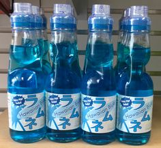 four bottled water bottles sitting on top of a wooden table next to another bottle filled with blue liquid