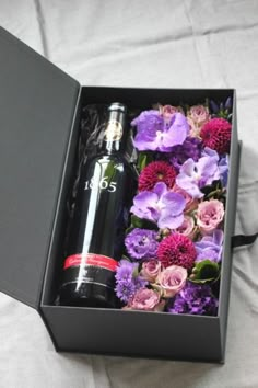 an open box with flowers and a bottle in it