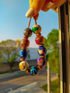 a person holding onto a beaded bracelet on a window sill with trees in the background