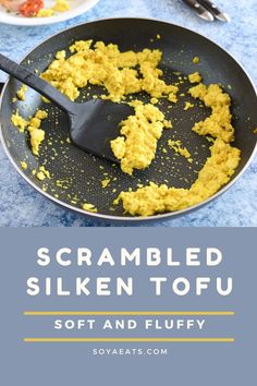 scrambled tofu in a skillet on a blue table with two plates of food