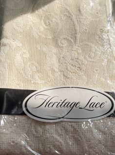 an antique lace label sitting on top of a piece of white fabric with black trim