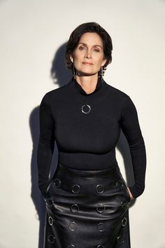 a woman in a black top and leather skirt posing for a photo with her hands on her hips