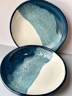 two blue and white bowls sitting next to each other