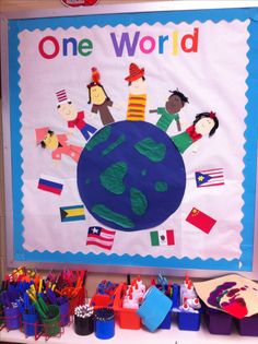 the bulletin board is decorated with children's drawings and flags, including one world