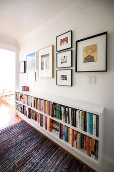 a bookshelf filled with lots of books on top of a wooden floor next to a window