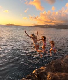 two girls jumping into the water at sunset