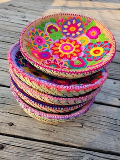 colorful bowls are stacked on top of each other in the middle of a wooden deck