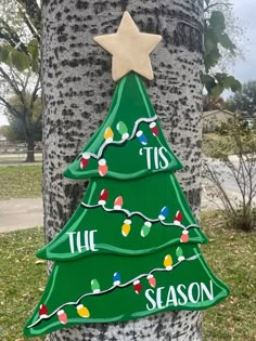 a green christmas tree with lights on it and the words tis is season painted on it