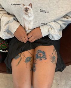 a person with tattoos on their legs and a cat sitting on top of her leg