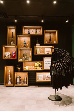 a display case with clothes hanging from it's sides in a room filled with wooden shelves