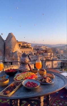 a table topped with plates of food next to a bowl of fruit and orange juice