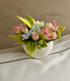 a white vase filled with flowers on top of a bed