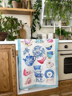 a tea towel hanging on the wall in a kitchen with potted plants behind it