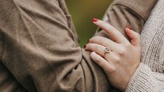 two people holding each other's hands with their arms wrapped around them, both wearing rings