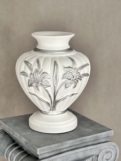 a white vase sitting on top of a table next to a stack of marble blocks