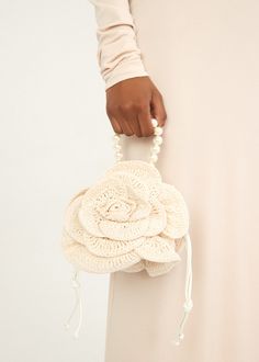 a woman is holding a crocheted purse with flowers on it's handle