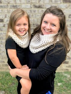 a mother and daughter hugging each other in front of a brick wall