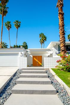 a white house with palm trees in the background and steps leading up to the front door