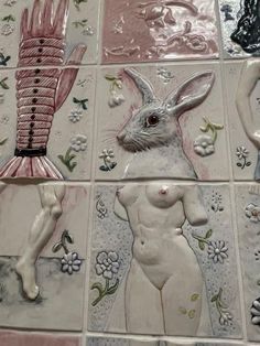 some ceramic artwork on a tiled wall with flowers and birds in the background, as well as an image of a naked woman