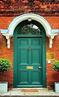 a green door with two planters in front of it and an arch above the door