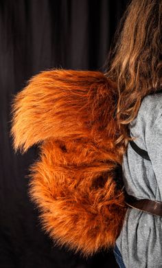 an orange furry animal tail on a woman's back with her hands in her pockets