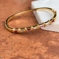 Estate/ Vintage 18KT Yellow Gold Designer Bangle Bracelet with Channel Set Pink/ Red Ruby + Diamonds. Excellent estate condition Hinged Push In, with safety latch, very secure Weight: 19 Grams Diamonds: .90 carat total weight Baguette-Cut Ruby + Diamonds VS clarity; G H Color Measures: 60mm in diameter 4.7-3mm wide front Designer Marked 18KT MW Luxury Red Baguette Diamond Jewelry, Panther Jewelry, Ruby Bracelet, White Gold Bracelet, White Gold Necklaces, White Gold Earrings, Rose Gold Bracelet, Diamond Bangle, Yellow Gold Bracelet