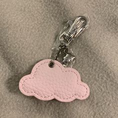 a pink cloud shaped keychain on a gray surface with a silver metal hook